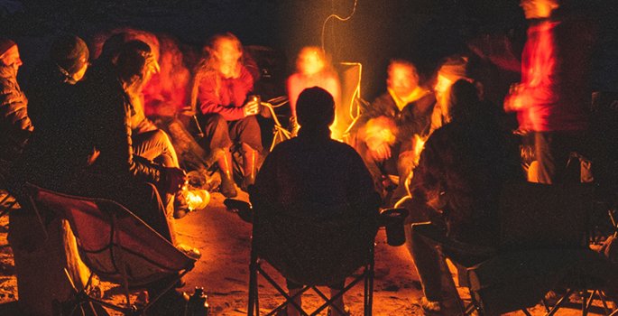 Group of people with chairs around a campfire